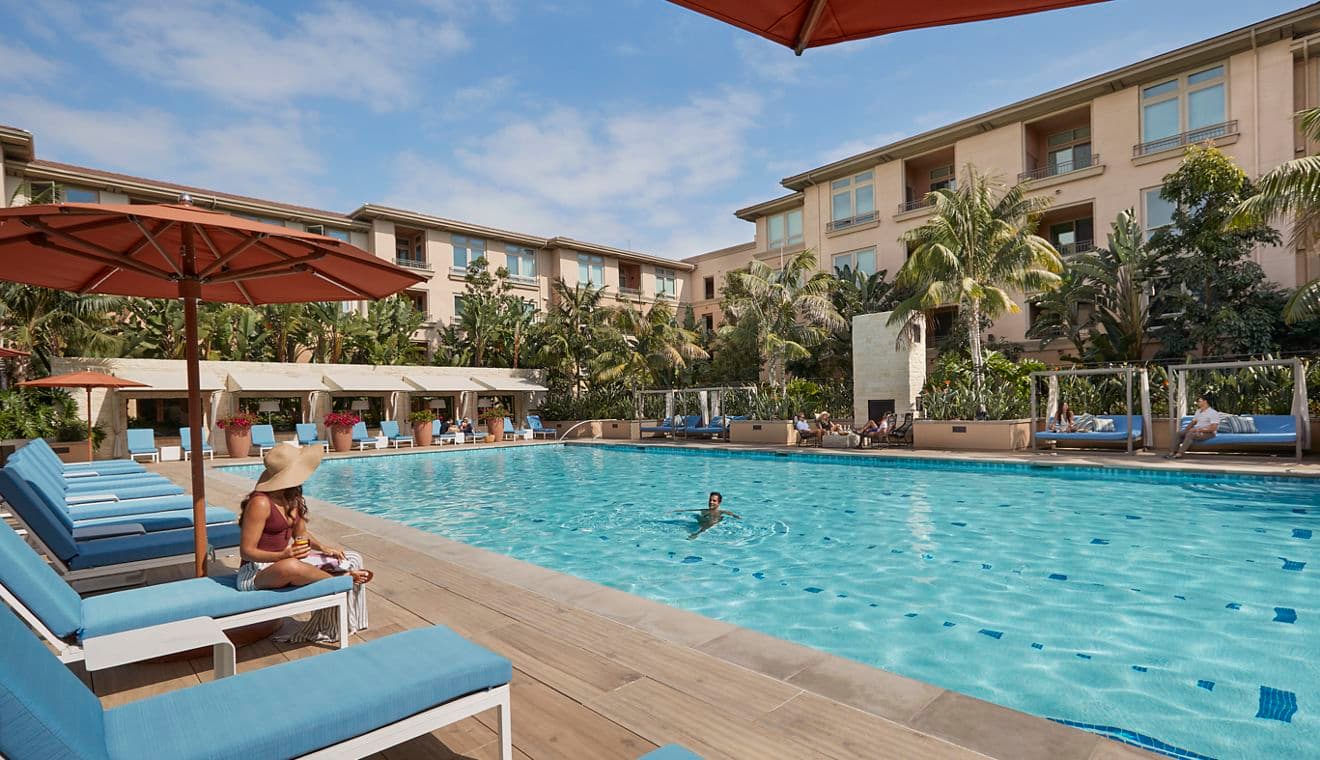 Exterior view of people spending time by pool at Villas at Playa Vista Apartment Homes in Playa Vista, CA.