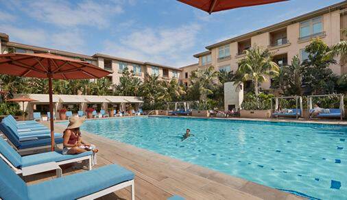Exterior view of people spending time by pool at Villas at Playa Vista Apartment Homes in Playa Vista, CA.