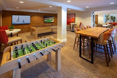 Interior view of game room with foosball table at The Cypress at North Park Apartment Homes in San Jose, CA.