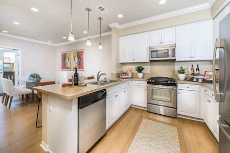 Interior view of kitchen and dining room at Los Olivos Apartment Homes at Irvine Spectrum in Irvine, CA.
