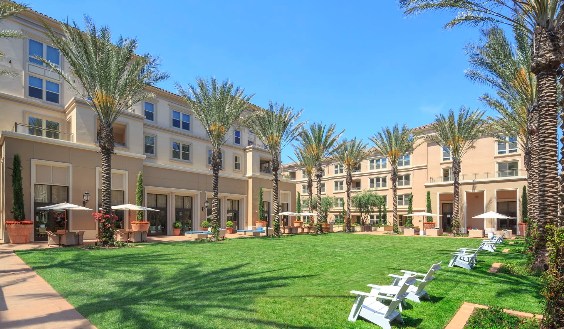 Exterior view of lawn and lounge area at Villas Fashion Island Apartment Homes in Newport Beach, CA.