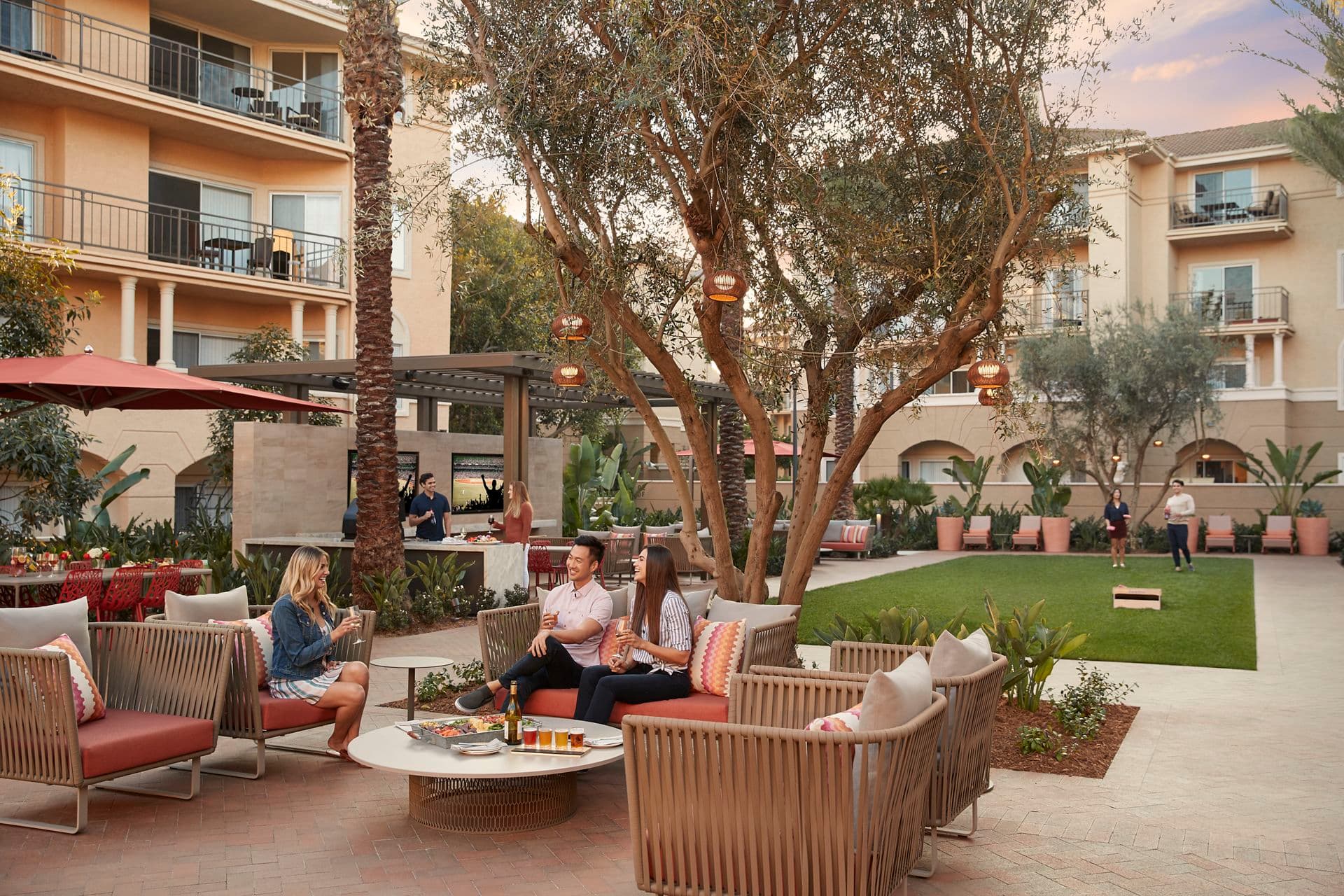 Exterior view of people spending time in lounge courtyard at The Villas of Renaissance Apartment Homes in San Diego, CA.
