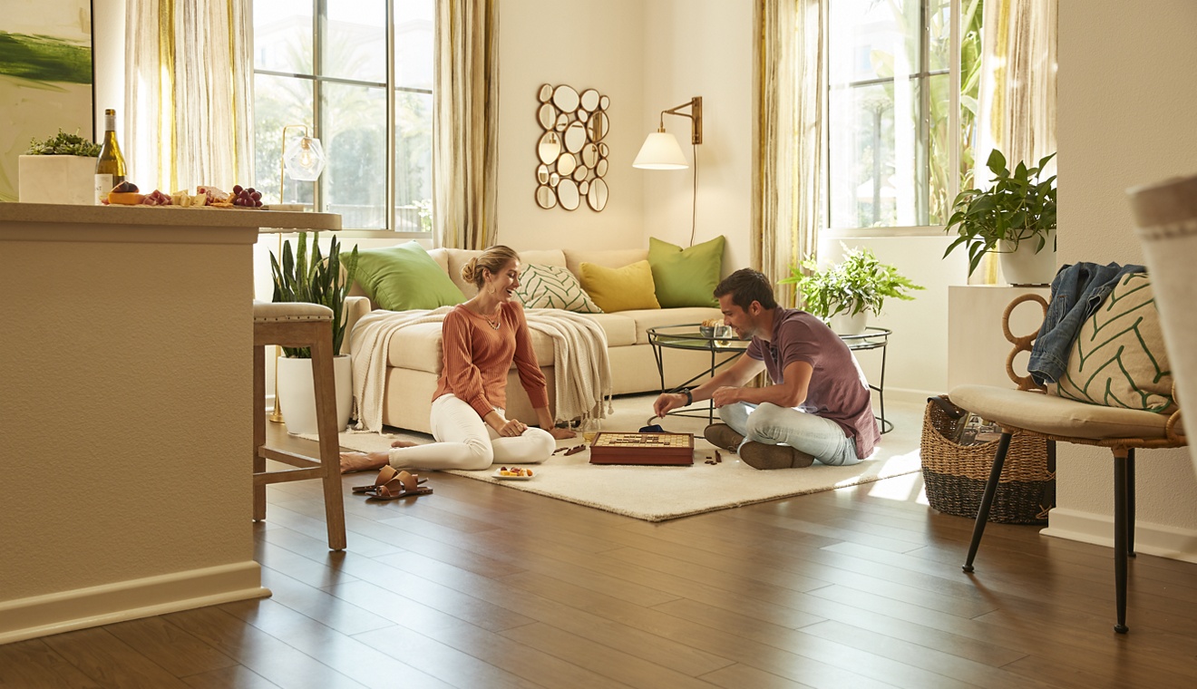 Interior view of couple playing board game in living room at Irvine Company Apartment Communities.