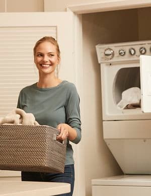 Interior view of woman holding a laundry basket in laundry room at Irvine Company Apartment Communities.