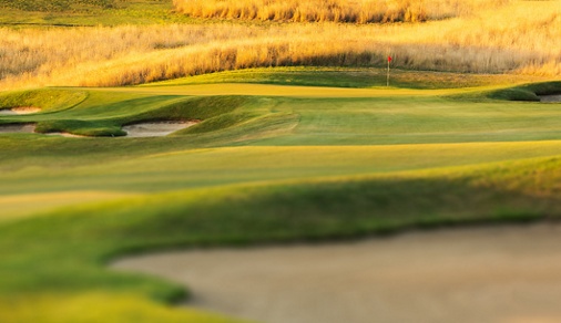 Golf Coarse at sunset with bunker, green and pin in view