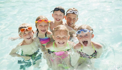Image of kids smiling in a swimming pool.