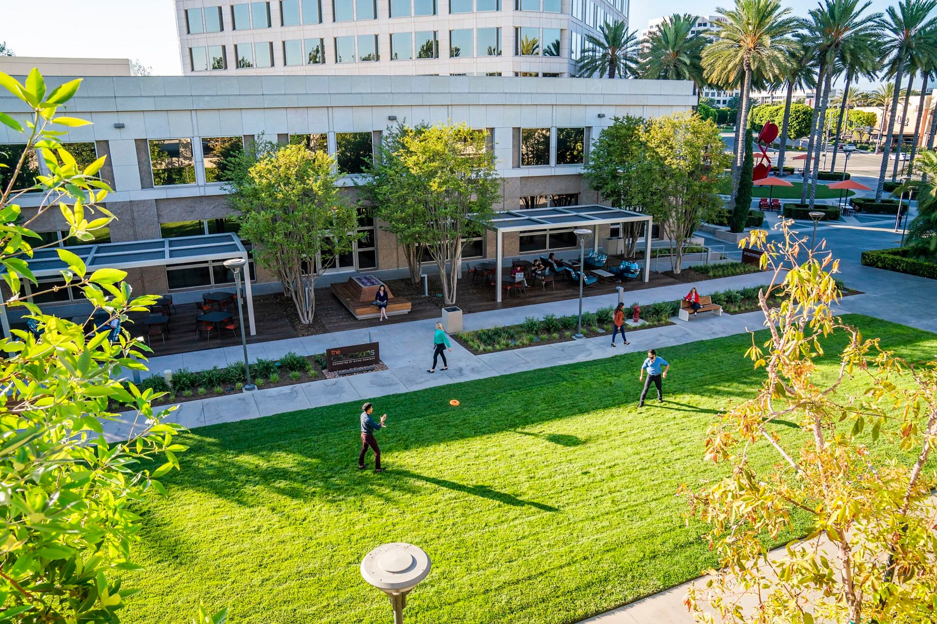 Exterior view of people at The Commons outdoor workspace at the 100 Spectrum Center Drive office building in Irvine, CA.