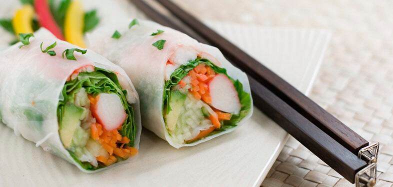 Two hand rolled temaki style sushi rolls filled with vegetables, surimi and ebi.  Shallow dof.